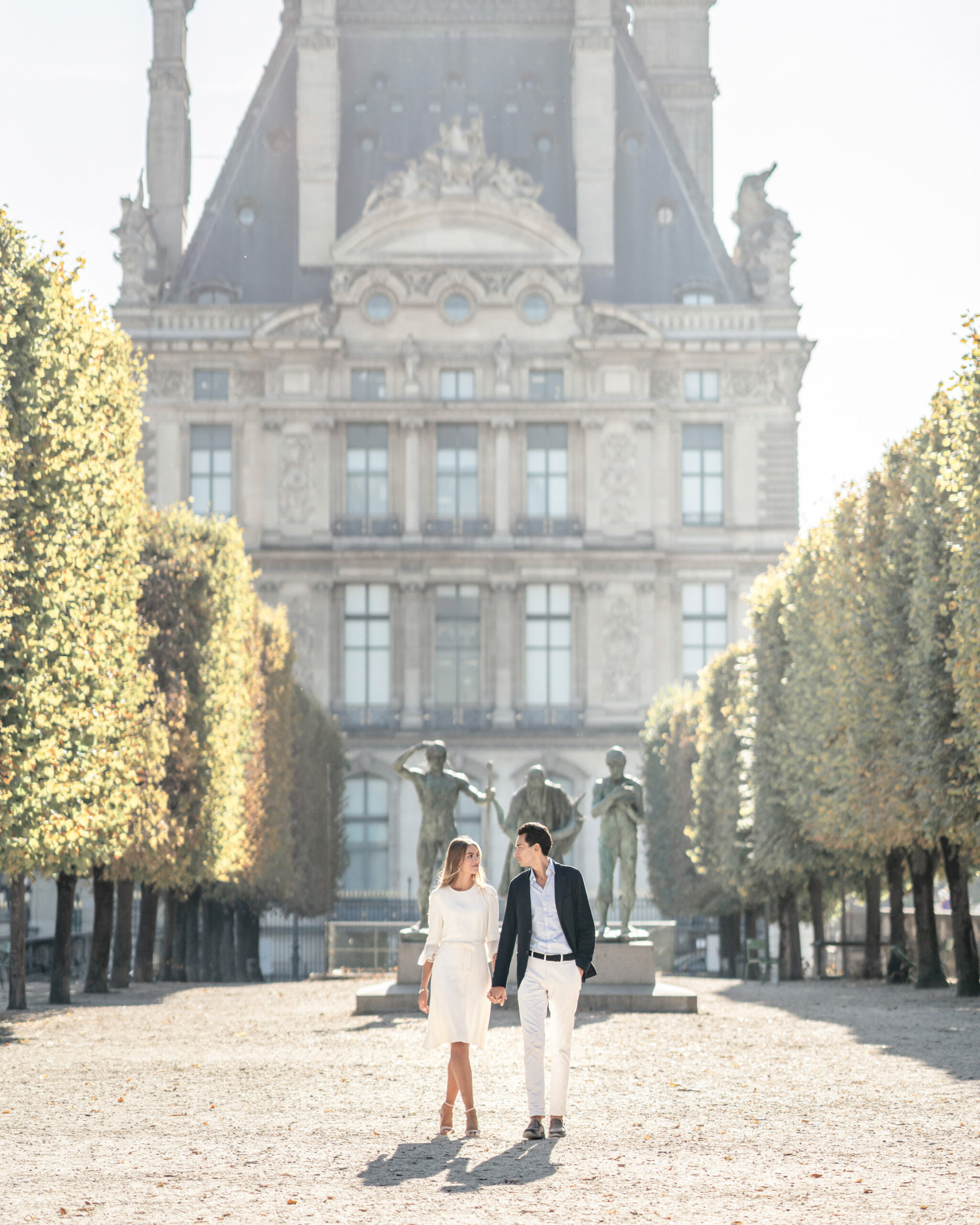 Couple walking down the tree lined path through the park near the Louvre in Paris