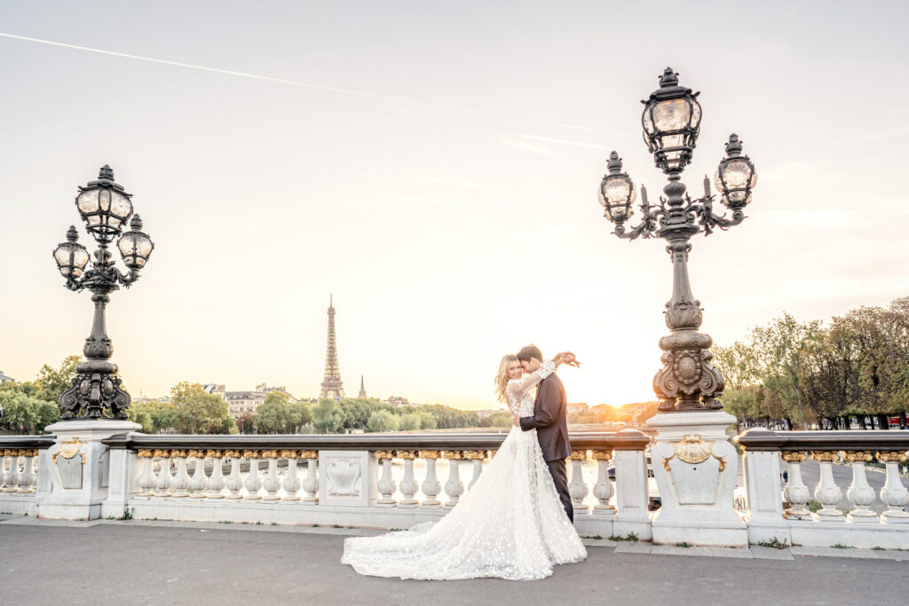 Bride and groom posing on the Pont Alexandre III bridge in Paris with the Eiffel tower in the background