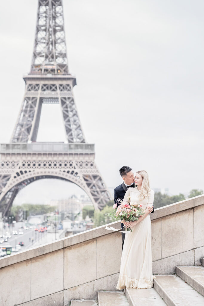 Bride and goom posing on the steps in front of the Eiffel Tower