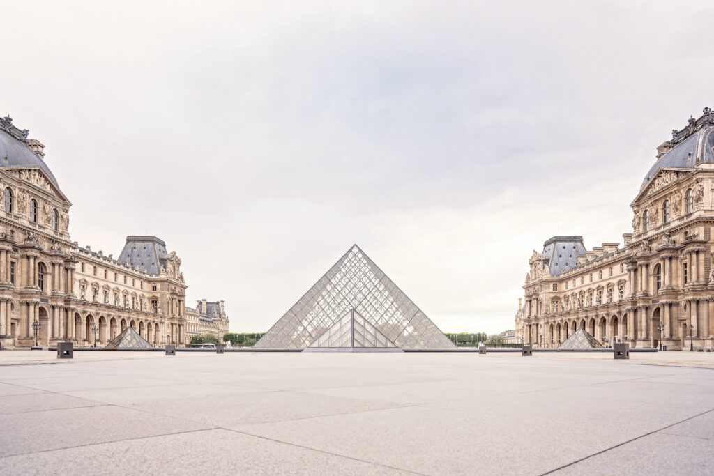 Landscape photo of the Louvre museum in Paris and it's large glass pyramid
