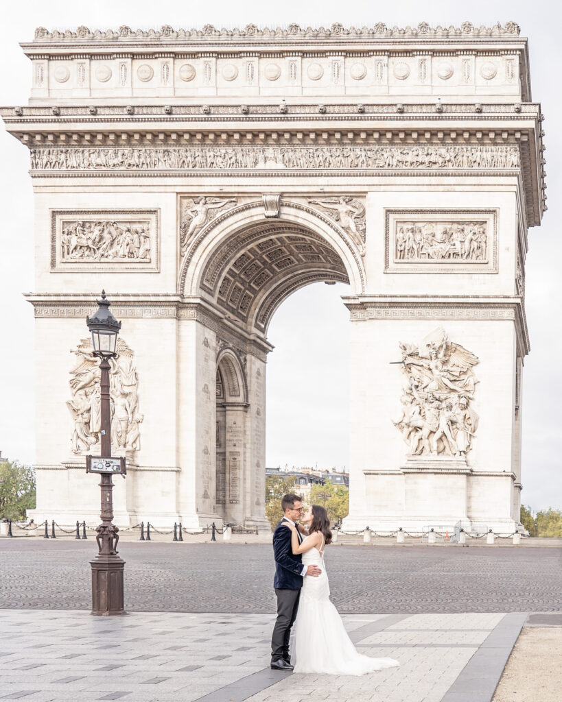 Bride and groom posing in front of the Arc de Triomphe in Paris