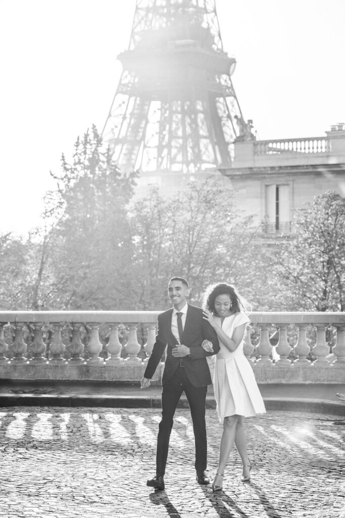 Couple walking arm in arm and smiling in front of the Eiffel Tower in Paris
