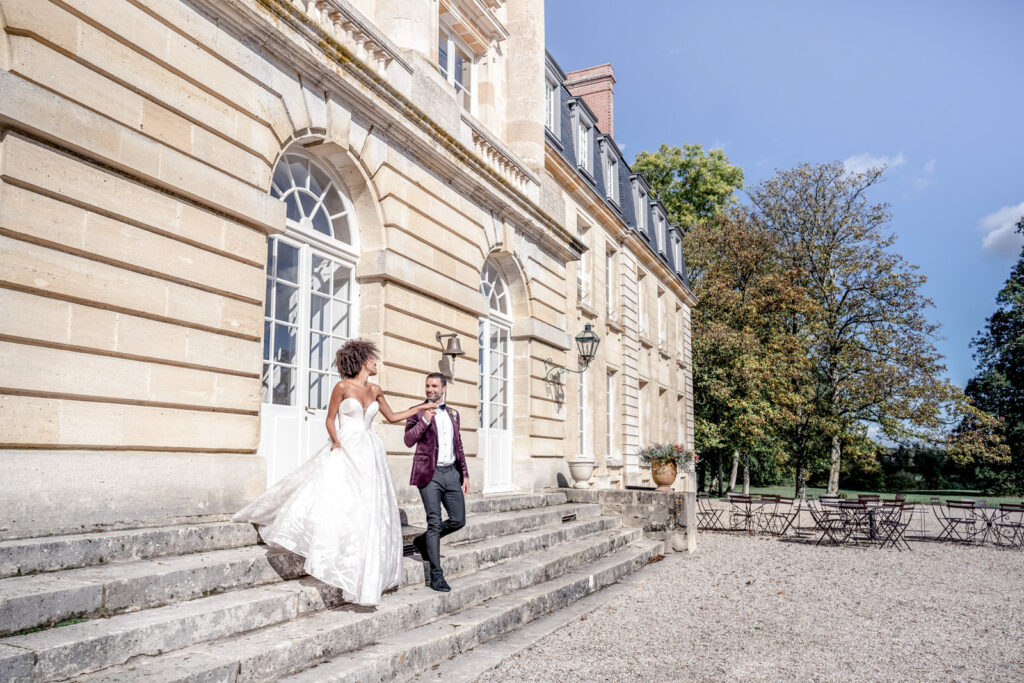Bride and groom walking down the front steps at Chateau de Courtomer estate in Normandy, France.