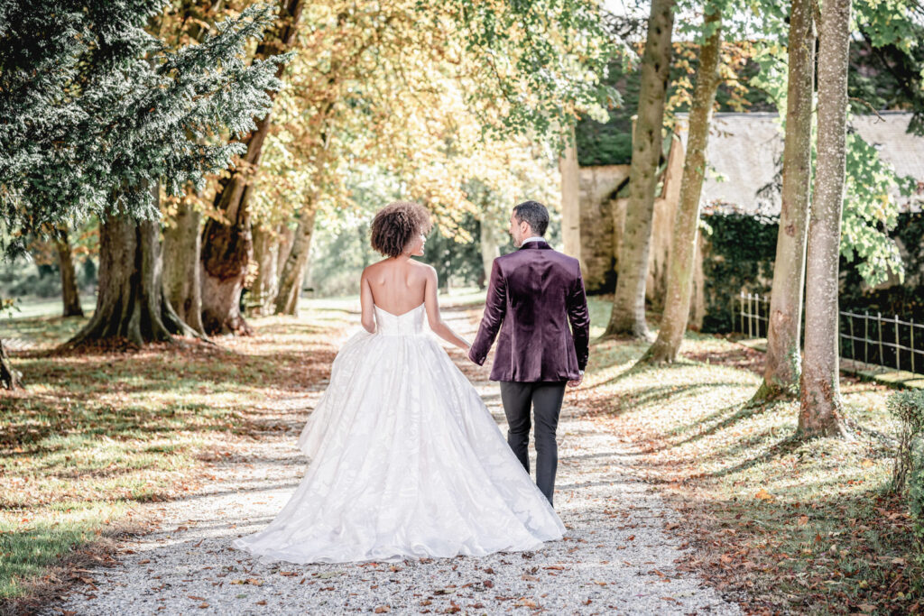 Bride and groom walking through the woodland at the at Chateau de Courtomer estate in Normandy, France.