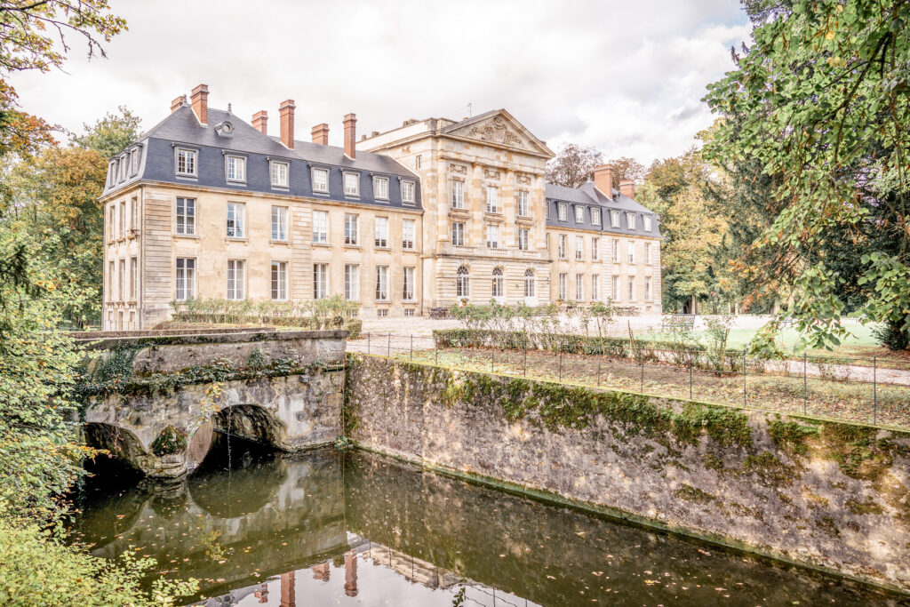 The exterior of wedding venue Chateau de Courtomer in Normandy, France with the moat in the foreground.