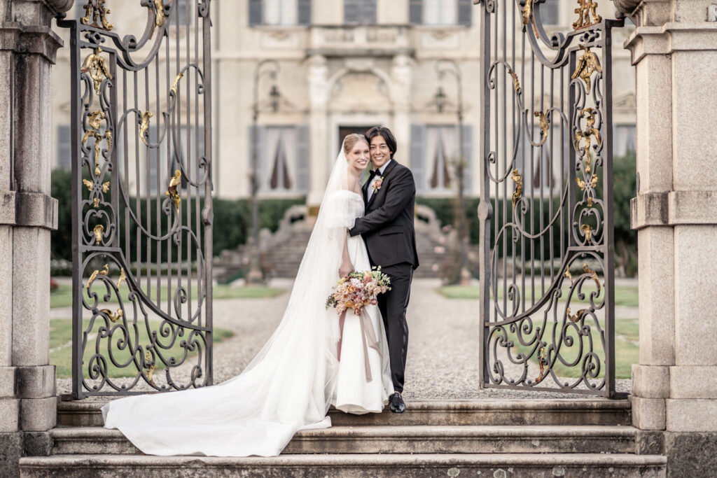 Bride and groom standing by the front gates at villa sola cabiati