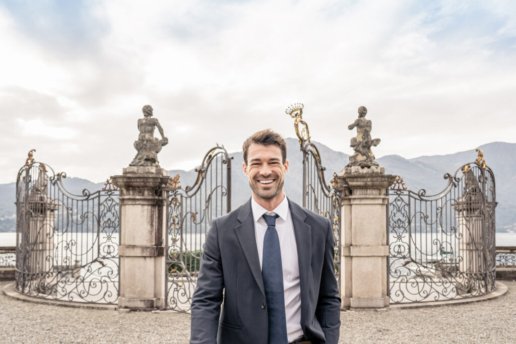 Groom walking up the path in front of the gates in the gardens of villa sola cabiati on lake como