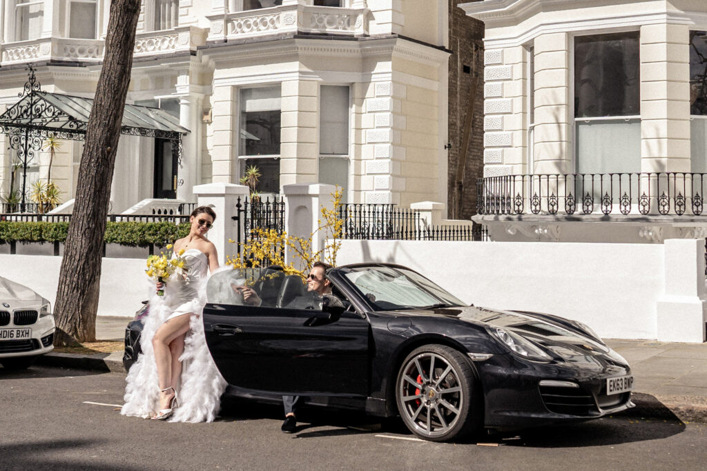 Bride and groom posing next to a convertible porsche car in Notting Hill in London