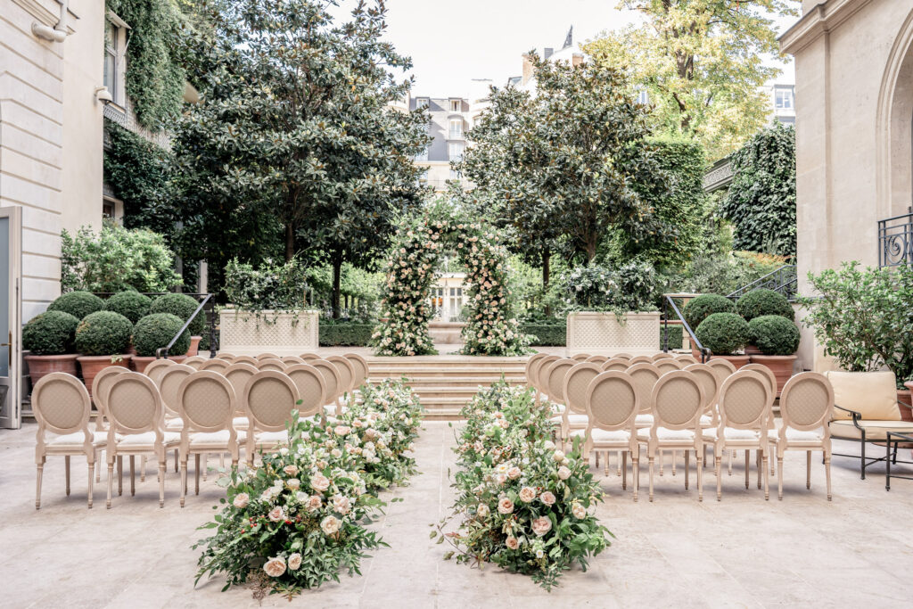 The Salon d'Été terrace set up for an outdoor wedding with floral arch and flowers down the aisle