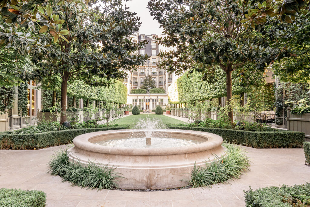 The Grand Jardin at the Ritz Paris Hotel with water feature, grass and trees
