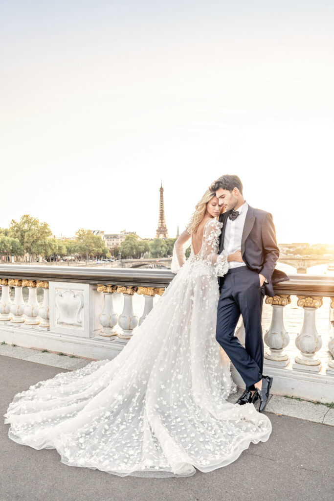Bride and groom posing at sunset on the Pont Alexandre III bridge in front of the Eiffel tower in Paris