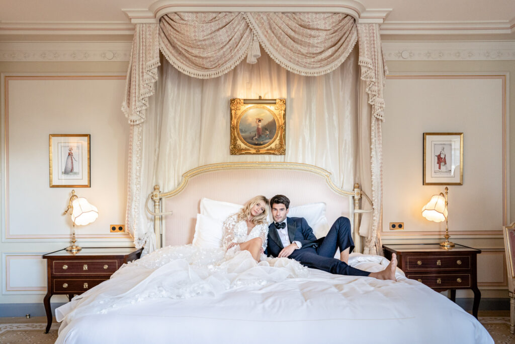 Bride and groom posing on the bed in one of the suites at the Ritz hotel in Paris