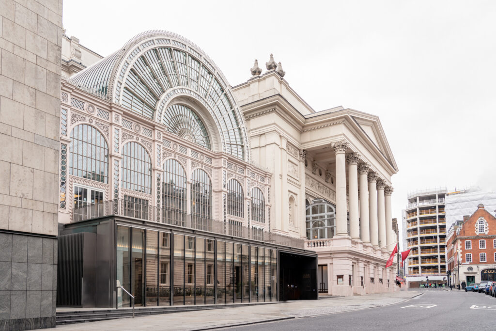 Facade of the outside of the Royal Opera House in London with the large glass oval dome and columns
