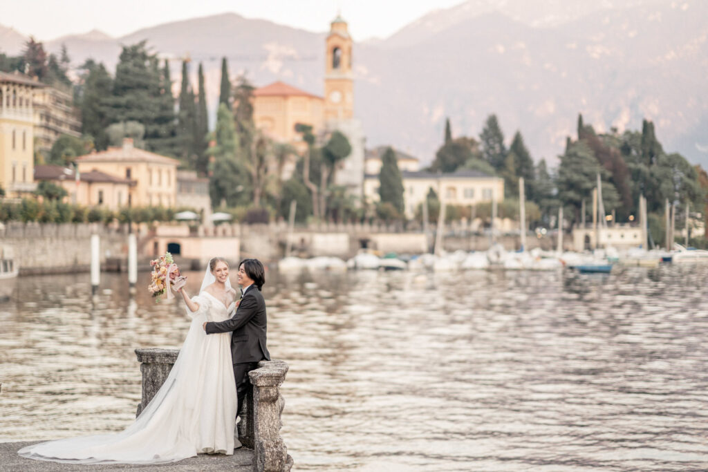 Bride and groom posing next to Lake Como in Italy