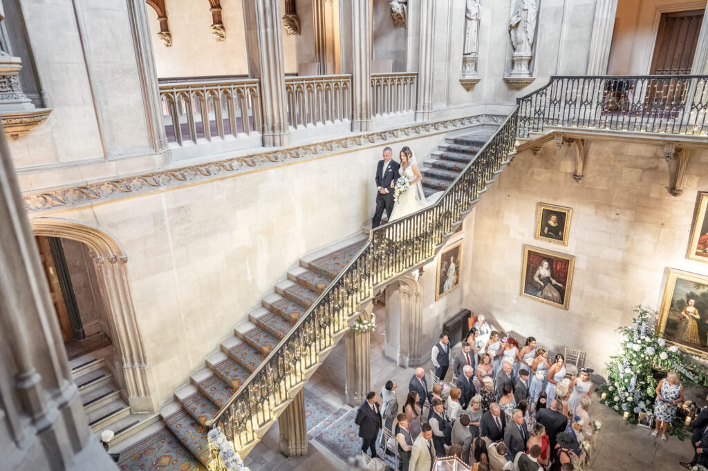 Father and bride walking down the stairs towards the aisle at Ashridge House