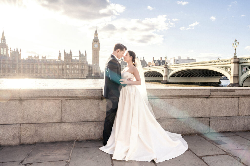 Bride and groom posing in hold in front of Big Ben and the Houses of Parliament in London.