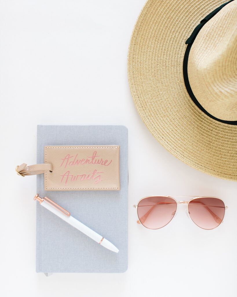 Flatlay of a sunhat, pad & pen and sunglasses