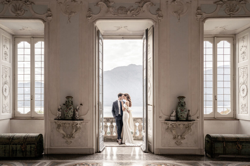 Bride and groom posing together on the balcony at Villa Sola Cabiati in front of Lake Como in Italy.