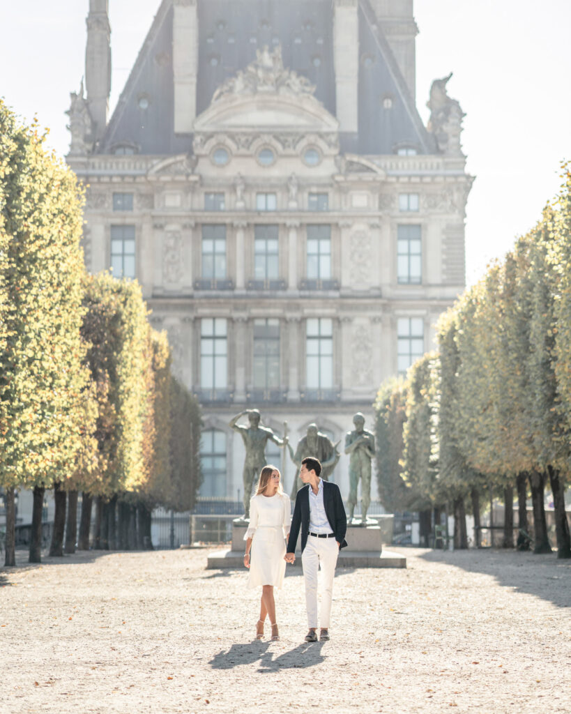 Bride and groom walking along the tree lined walkway at the Tuilleries gardens in front of the Louvre.