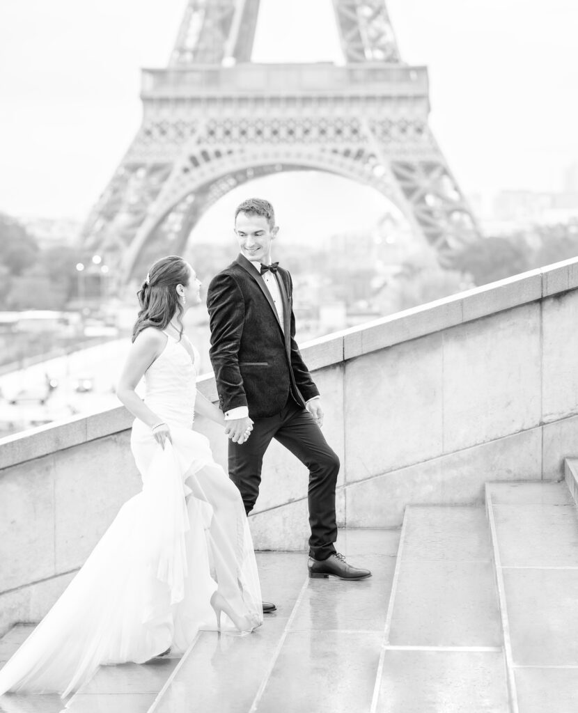 Bride and groom walking hand in hand up stone steps in Paris in front of the Eiffel Tower