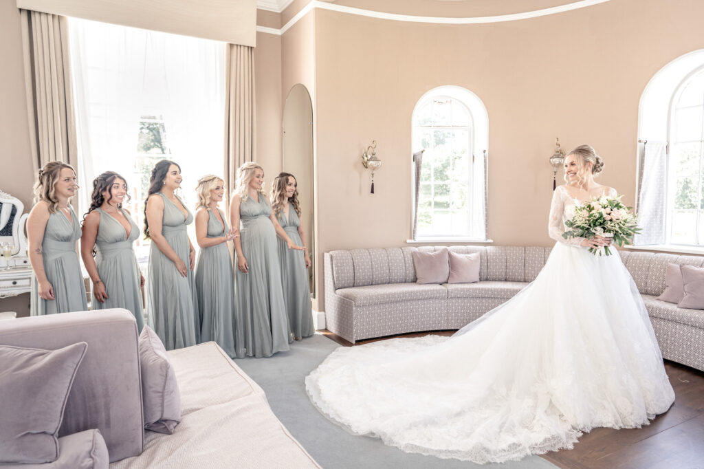 Bride looking back at her bridesmaids as they see her in her wedding dress for the first time