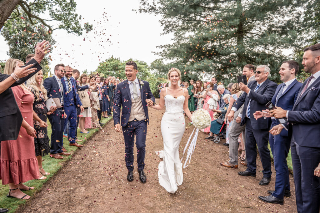 Bride and groom walking through their guests to confetti