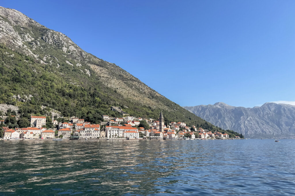 An old town of Montenegro next to the sea with a mountain backdrop