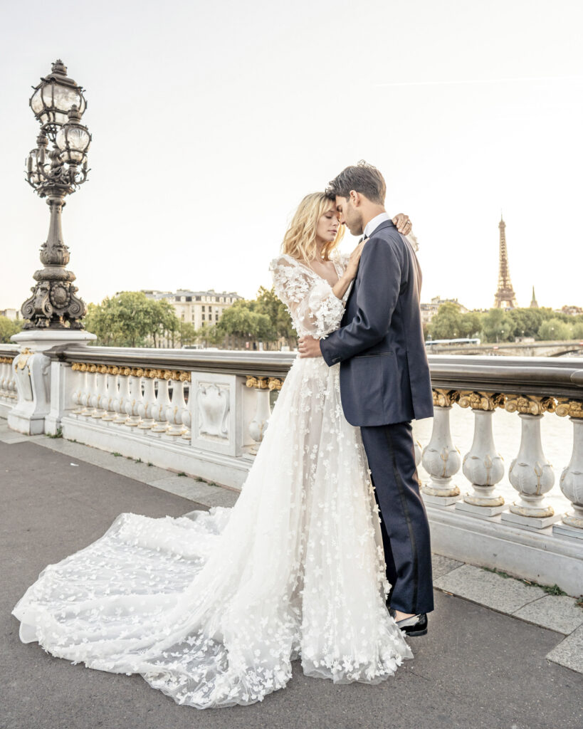 Bride and groom posing in each others arms in front of the Eiffel Tower in Paris.