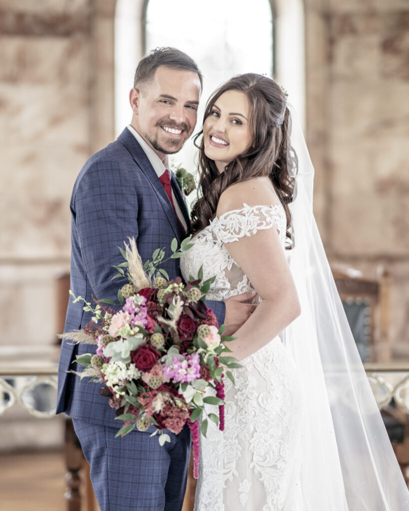 Bride and groom posing in each others arms and smiling to camera at Hawkstone Hall in Shropshire.