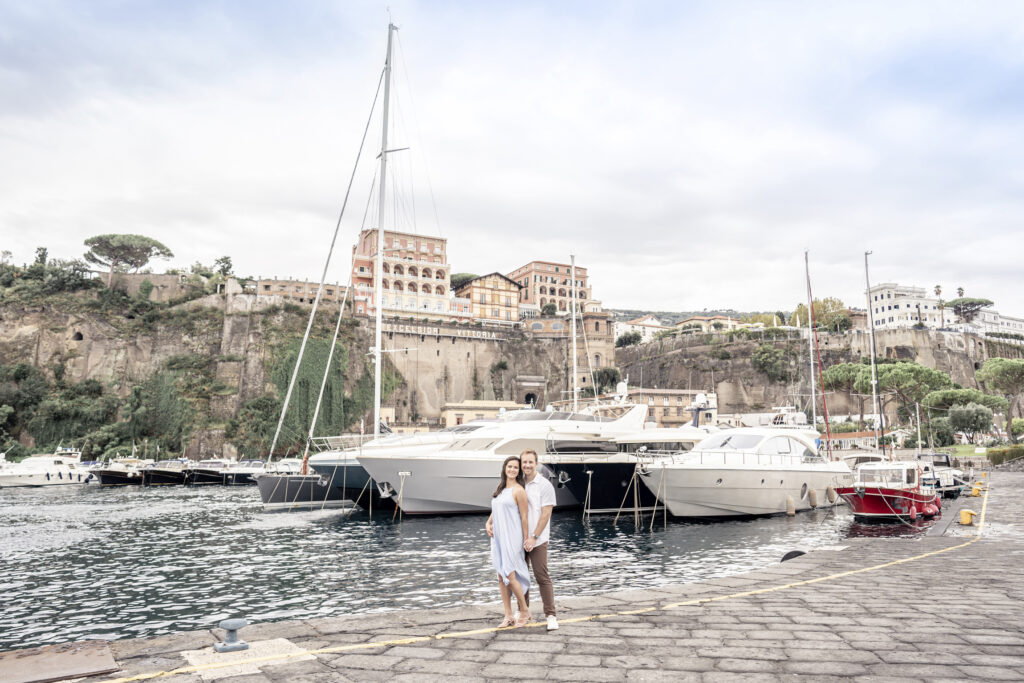 Engagement portrait of a couple in front of a yacht on the Amalfi Coast.