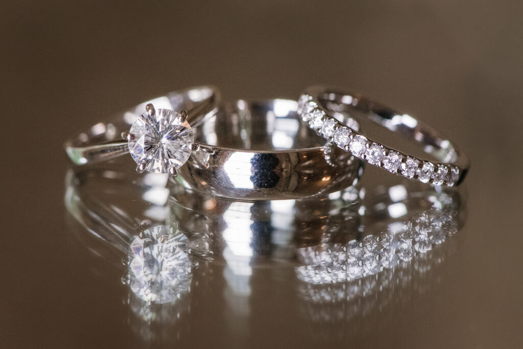 Close up photo of his and hers wedding rings and a diamond, platinum ring