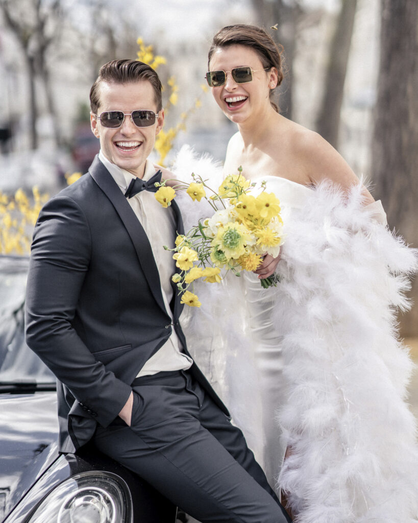 Bride and groom sitting on the Porsche wearing sunglasses in the sunny French Riviera.