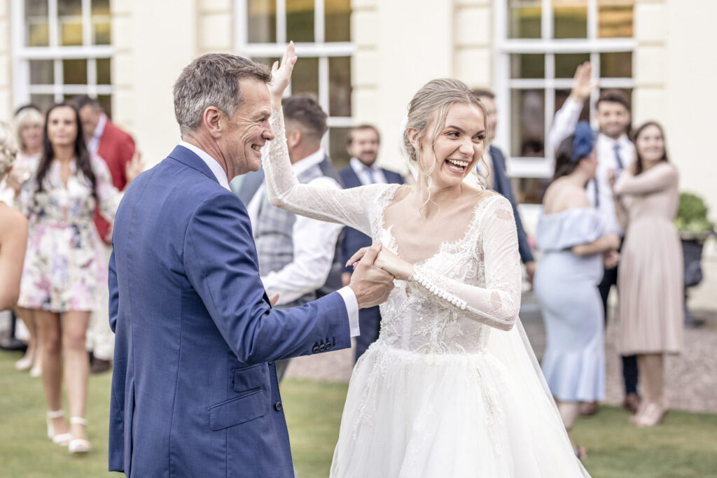 Bride and father of the bride dancing in the evening of the wedding in the gardens at Hawkstone Hall wedding venue in Shropshire.