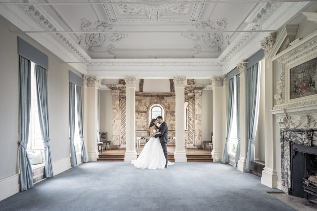 Bride and groom posing by the columns in the Tapestry Room at Hawkstone Hall wedding venue in Shropshire.