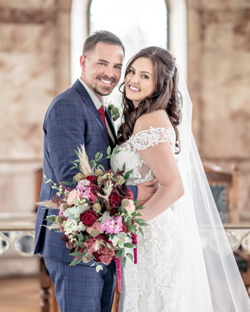 Bride and groom posing together and smiling to camera in the blue room at Hawkstone Hall in Shropshire.