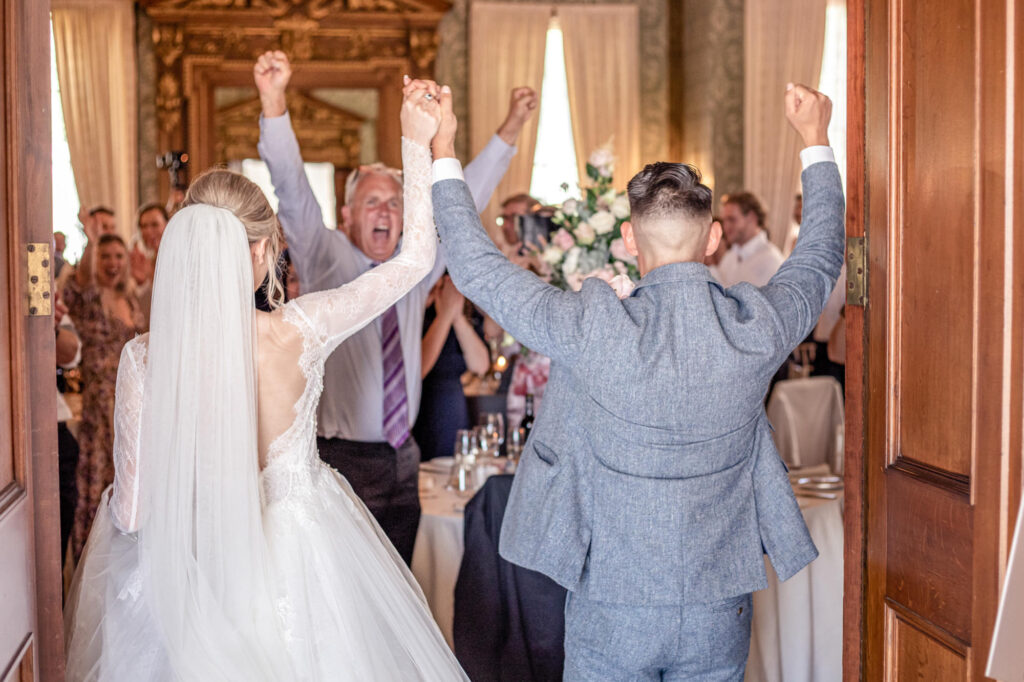 Bride and groom walk into the ballroom at Hawkstone Hall to huge cheers from their wedding guests