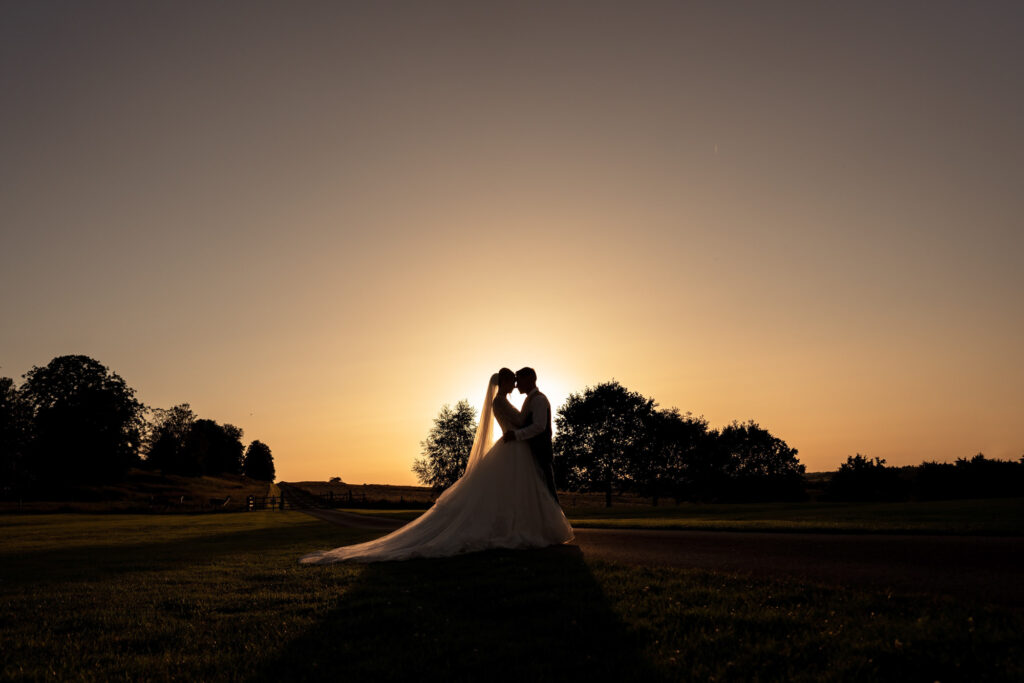 Bride and groom silhouette at sunset golden hour in the gardens of Hawkstone Hall in Shropshire