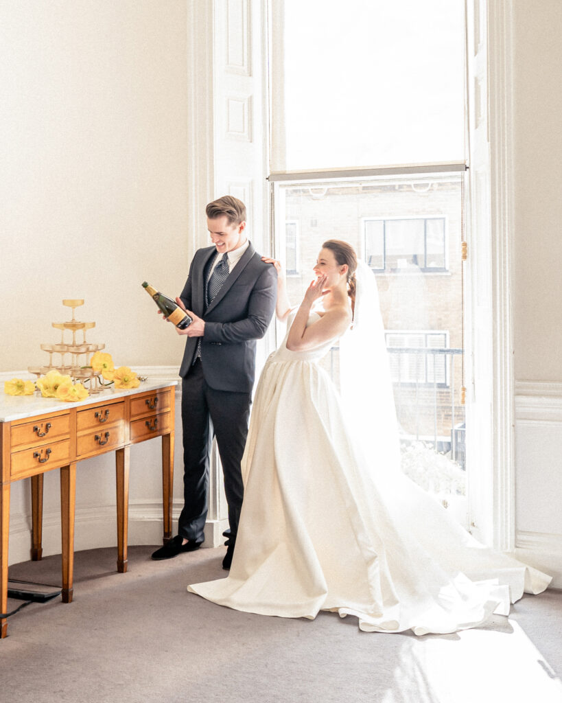 Bride and groom popping open a bottle of bubbly in London for a champagne fountain