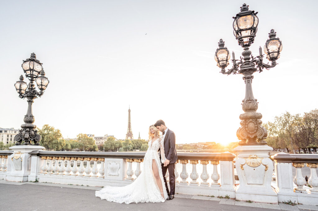 A bride and groom posing together on the Pont Alexandre III bridge overlooking the Eiffel Tower in Paris