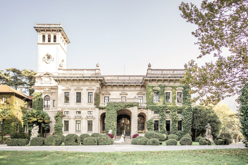 A bride and groom posing together on the steps outside of Villa Erba on Lake Como in Italy