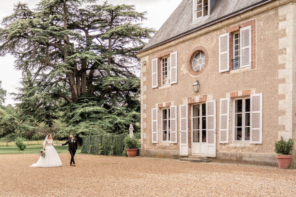 A bride and groom walking hand in hand towards Chateau de Bouthonvilliers in France