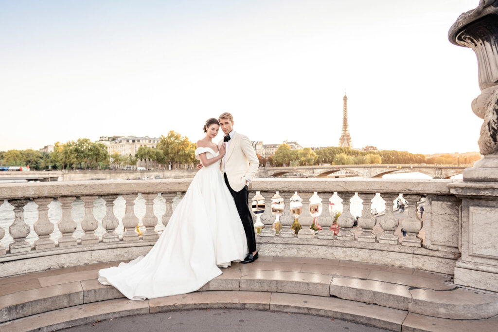 A bride and groom posing together on the Pont Alexandre III bridge overlooking the Eiffel Tower in Paris