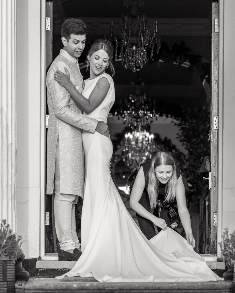 Photographer, Victoria Amrose, helping lay out the bride's wedding dress for portraits