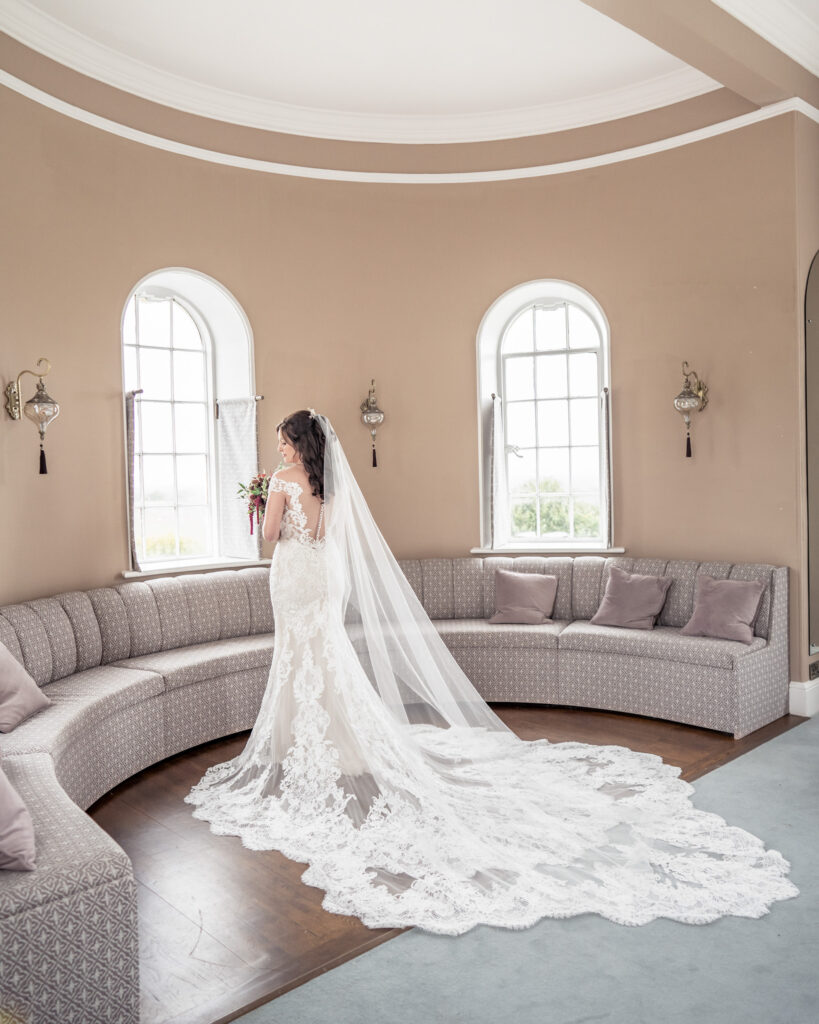 Photo of a beautiful bride stood at the window in the bridal suite at Hawkstone Hall in Shropshire.