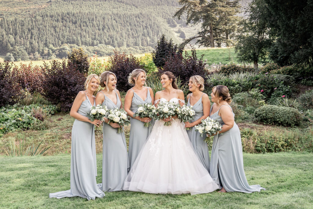 Bride and her bridesmaids posing together for a group photograph in the gardens of Tyn Dwr Hall.