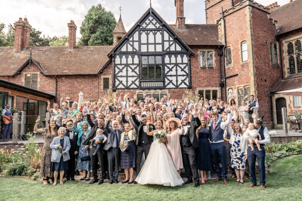 A full group photo of all wedding guests on the rear outdoor steps at Tyn Dwr Hall.