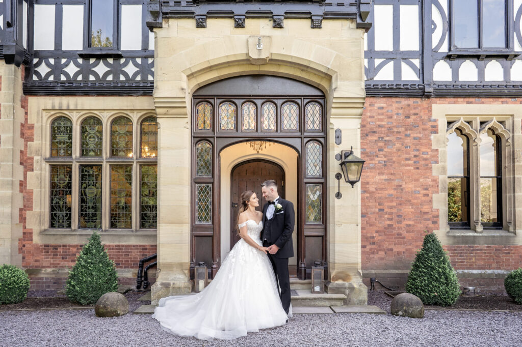 Bride and groom posing together outside the front door of Tyn Dwr Hall.