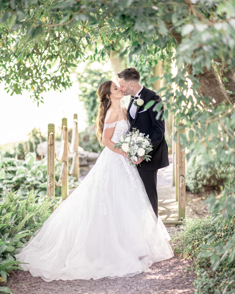 Bride and groom kissing in the woodland at Tyn Dwr Hall.