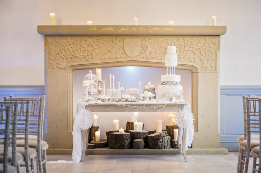 The fireplace in the ballroom at Tyn dwr Hall with a wedding cake table in front.