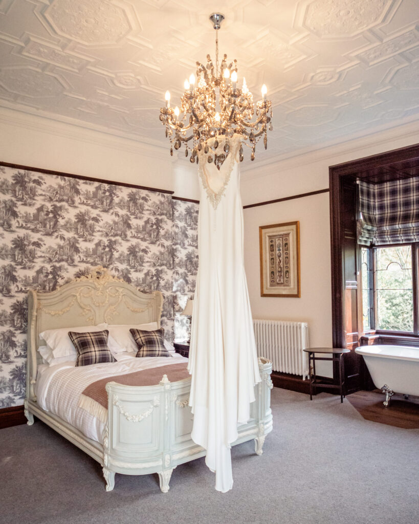 Wedding dress hanging from a crystal chandelier in the bridal suite at Tyn Dwr Hall.